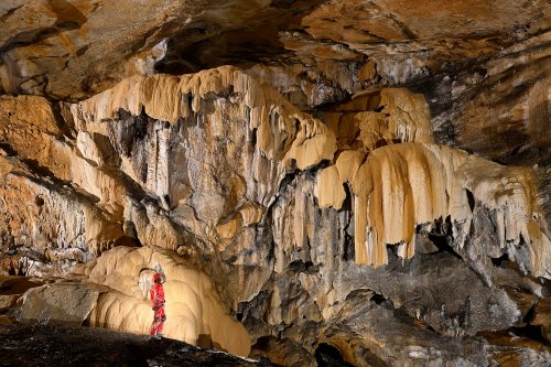 Cueva Fresca (Cantabrie, Espagne) - Coulées de calcite en cascade  suspendues sur une paroi avec personnage au pied.(SP-26-0931)